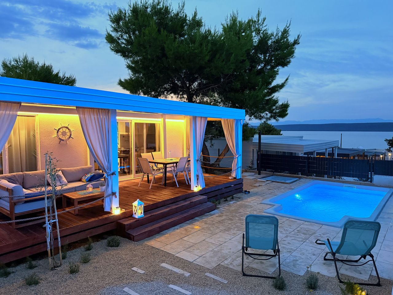 Private heated pool beside the covered terrace of a Salvia home at dusk in Neviđane on Pašman