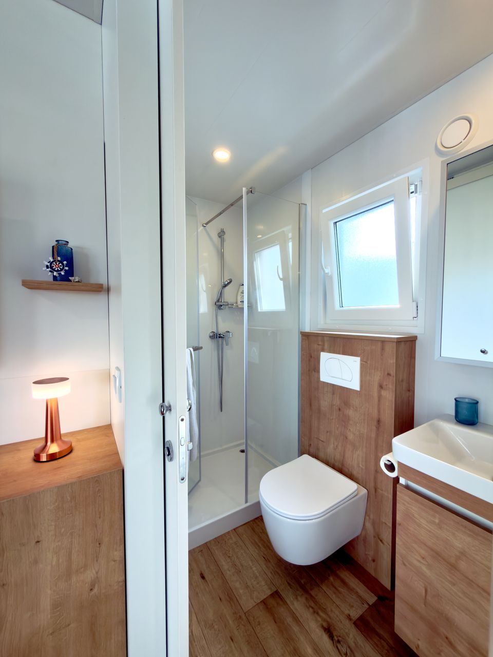 Modern bathroom with walk-in shower, toilet, and sink with wooden vanity at Salvia Beachside Homes