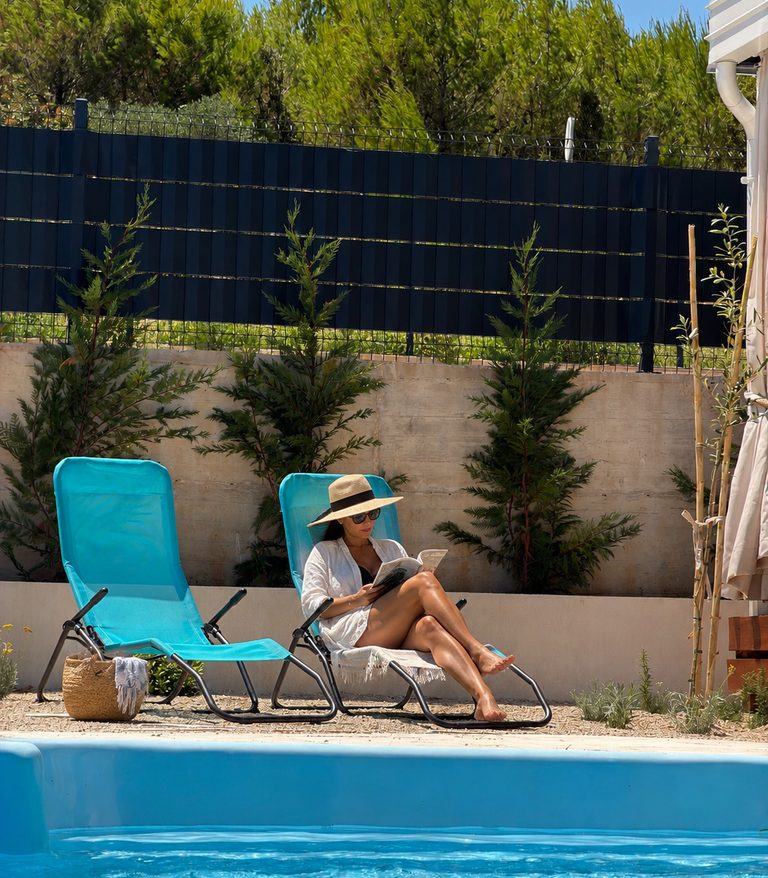 Guest reading on a sun lounger beside the private pool at Salvia Beachside Homes